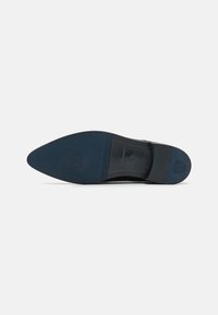 Sole di scarpa in pelle nera con forma a punta, design del logo in rilievo e suola in gomma blu. Presenta sezioni lisce e testurizzate.