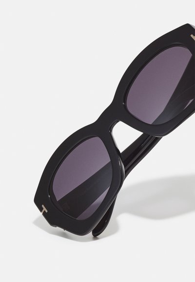 Occhiali da sole neri con montatura quadrata oversize, lenti scure sfumate e dettagli in argento sottile. Materiale in plastica liscia.