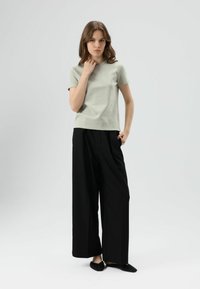 Lichtgroen t-shirt met korte mouwen, gecombineerd met zwarte wijde broekspijpen, met een ontspannen pasvorm, een gladde textuur en een eenvoudig ontwerp.