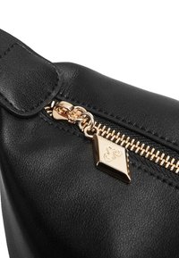 Borsa in pelle nera con una zip dorata ben visibile e un tirazip a forma di diamante con logo inciso. Texture liscia e forma strutturata.