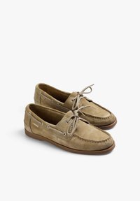 Scarpe da barca in camoscio di colore marrone chiaro con lacci beige, punta rotonda, dettagli di cucitura e occhielli in metallo, dotate di suola in gomma per una buona aderenza.