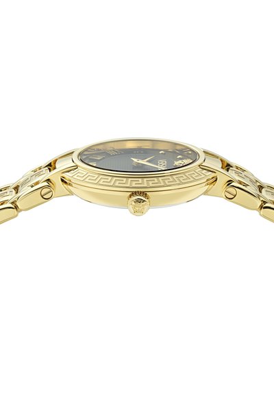 Goudkleurige horloge met een ronde wijzerplaat, zwarte dial, Romeinse cijfers en een gestructureerde band met een Grieks sleutelpuntpatroon en leeuwenkopaccenten.