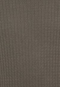 Gładka, teksturowana tkanina w ciemnym brązie z falistym wzorem. Posiada miękki, tkany wygląd, odpowiednia do tapicerki lub zastosowań dekoracyjnych.