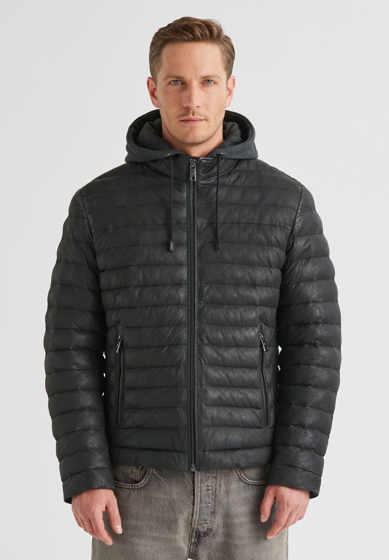 Schwarze Pufferjacke mit strukturierter Oberfläche, ausgestattet mit einer abnehmbaren grauen Kapuze, Reißverschlusstaschen vorne und gerippten Bündchen.