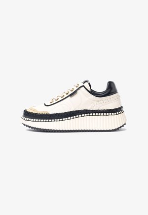 Plattform-Sneaker mit einem Obermaterial aus weißem Leder, schwarzen Akzenten und goldenen Ösen. Mit gewebten Details entlang der Sohle und einer gerippten weißen Basis.