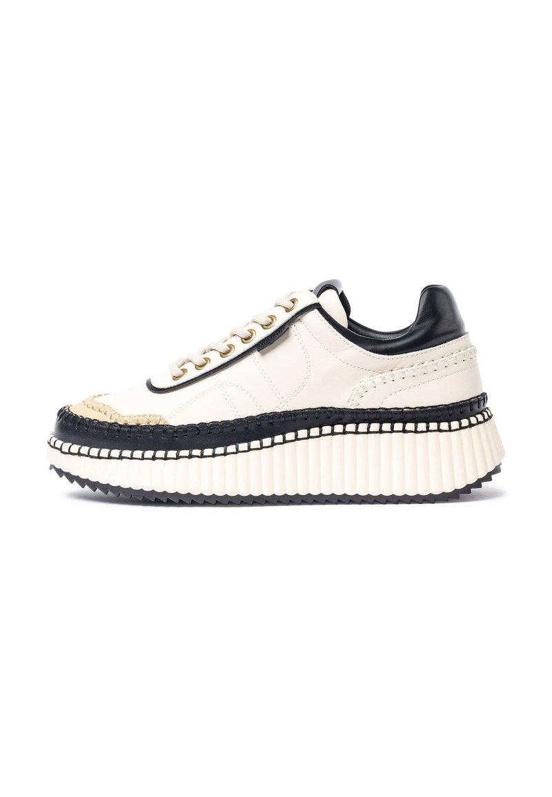 Sneaker platform con tomaia in pelle bianca, dettagli neri e occhielli dorati. Presentano dettagli intrecciati lungo la suola e una base bianca zigrinata.