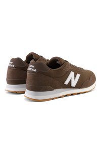 Paire de baskets New Balance marron avec semelles intermédiaires blanches, semelles extérieures en gomme et logo blanc "N" sur le côté, vue en angle arrière latéral.