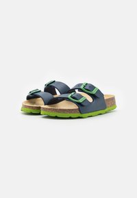 Mörkblå sandaler med gröna accenter, utrustade med två justerbara remmar, en korkfotbädd och en strukturerad grön gummisula.