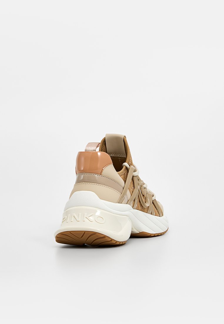 Baskets beiges avec une tige texturée, des accents brillants et une semelle rembourrée. Présente un design à lacets et une marque sur le talon.