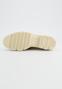 Semelle d'une chaussure beige avec une adhérence texturée, des rainures parallèles et un logo "pg" en relief, taille 4½, présentée sur un fond blanc uni.