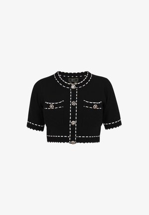 Cardigan noir court avec bords blancs cousus, présentant deux poches avant, un col rond et des boutons décoratifs au design floral.