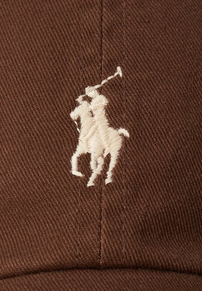 Gorra de béisbol marrón con un tejido texturizado, que presenta un logo bordado en blanco de un jugador de polo en el frente.