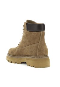 Botas de tobillo de ante marrón con un cuello de cuero marrón, punta redonda y suela gruesa de perfilado. Presentan ojales de metal y detalles de costura en contraste.