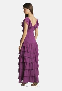Lila, gestuften Maxikleid mit Rüschärmen, tailliertem Oberteil und offenem Rücken, das eine transparente Textur und einen fließenden, geschichteten Rock aufweist.