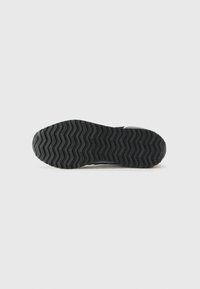 Semelle de chaussure en caoutchouc noir avec une texture en zigzag et une adhérence motif. Présente un bord lisse et arrondi avec un minimum de marquage.