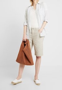 Vaaleanharmaa raidallinen nappipaita, kermaan vivahtava t-paita, beiget shortsit, ruskea mokkanahkainen laukku, valkoiset slip-on-kengät juuttipohjilla. Rento asu.