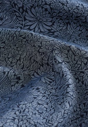 Marineblaue Stoff mit aufwendigen Blüten- und Blattmustern in einem helleren Farbton, der eine strukturierte Webart und glatte Optik zeigt.