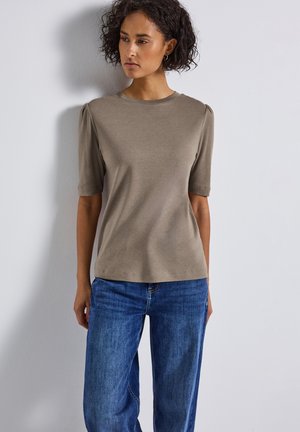 Haut gris clair à manches courtes avec épaules bouffantes, associé à un jean large bleu. Texture lisse, design simple, sans motifs ni quincaillerie visibles.