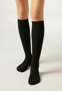 Zwarte kniehoge sokken van textiel met een chevronpatroon. Geribbelde bovenkant voor een stevige pasvorm.