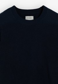 Granatowy sweter dzianinowy z okrągłym dekoltem i teksturowanym materiałem. Metka głosi "SCALPERS." Posiada ściągacze przy mankietach i u dołu.