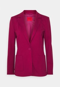 Blazer femme magenta à un bouton avec revers à crans, poches plaquées devant et étiquette rouge Hugo à l'intérieur du col.