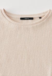 Beige ribbad stickad topp med rund halsringning. Taggen säger "någon gång." Texturen har vertikala ränder och en mjuk känsla.