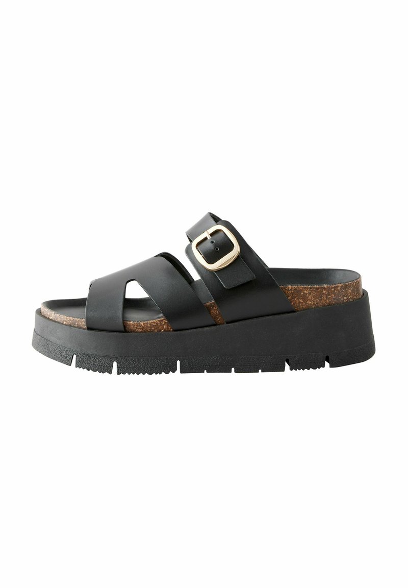 Sort lædersandal med to brede stropper, korksål og en kraftig sort ydersål. Har en guldbeslag accent for justering.