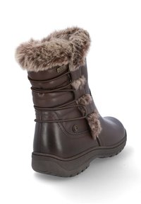 Botas marrones impermeables con ribete de pelo sintético, punta redondeada, suela de goma texturizada y cordones decorativos en la parte trasera. Parte superior de cuero suave.