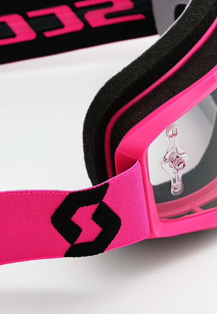 Okulary ochronne z różową ramką i różowym paskiem, wyposażone w przezroczyste soczewki, czarne akcenty oraz miękką piankową wyściółkę dla komfortu. W zestawie regulowany pasek.