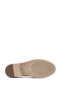 Suela de zapato con un material liso de color marrón claro que presenta surcos sutiles y un patrón circular elevado hacia el talón para proporcionar tracción.