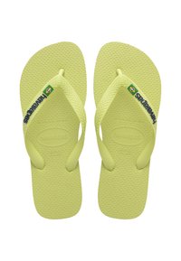 Šviesiai žali guminiu flip-flopu, su tekstūruotu padu, Y formos diržais ir „Havaianas“ prekės ženklu. Brazilijos vėliavos detalė kairiajame dirže.