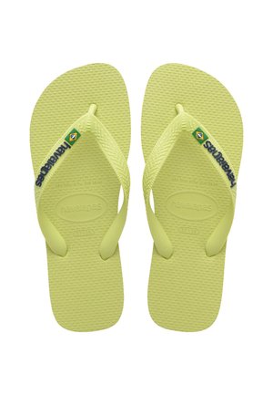 Infradito in gomma verde chiaro con fondo testurizzato, cinturini a forma di Y e marchio "Havaianas". Dettaglio della bandiera brasiliana sul cinturino sinistro.