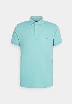 Hellblaues Poloshirt mit kurzen Ärmeln, drei weißen Knöpfen und kleinem rechteckigem Logo auf der linken Brust.
