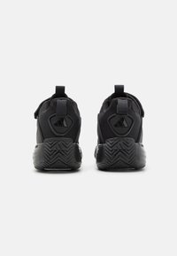 Schwarze Sportschuhe mit einem Mesh-Obermaterial, gepolstertem Kragen, Heel Pull Tab und einer strukturierten Gummisohle mit Zickzackmuster.