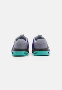 Scarpe sportive con una tomaia a intreccio viola, dettagli grigi, tallone nero e suola verde. Presentano una linguetta e il marchio "HYPERLIFT" sul lato.