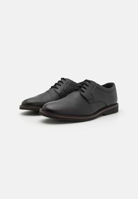 Schwarze Lederdressschuhe mit glatter Oberfläche, abgerundeter Zehenpartie und dezenten Nähdetails; verfügen über ein niedriges Profil und eine dünne, kontrastierende Sohle.