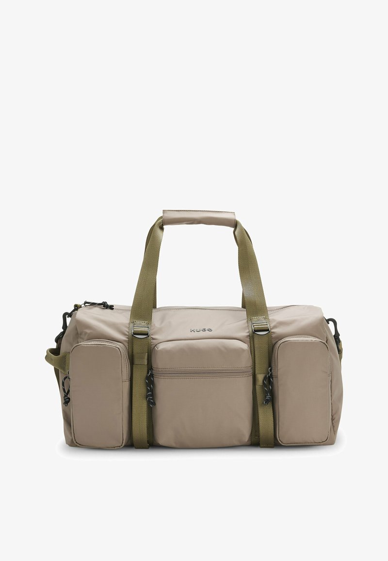 Sac fourre-tout beige avec trois poches avant zippées, bandoulières vert olive et une poignée rembourrée, marqué "HUGO" au centre avant.