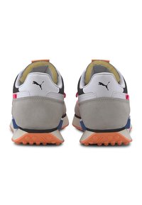 Paire de baskets Puma vues de dos, avec une tige en suède gris, blanc et noir, et des accents de semelle bleus et orange.