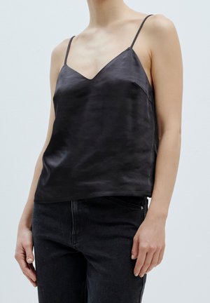 Zwarte satijnen camisole met dunne verstelbare bandjes, V-halslijn en een soepele textuur, gecombineerd met donkere spijkerbroek.
