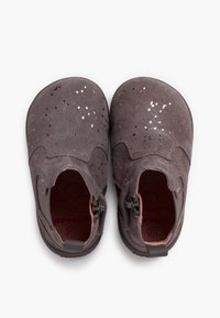 Scarpe per bambini in suede grigio con design perforato e piccoli dettagli metallici, dotate di zip laterali per una facile calzata.