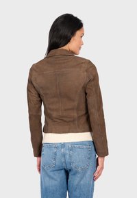 Hnědá bomber bunda z faux kůže s přiléhavým střihem, strukturovanými švy a zkrácenou délkou. Žebrovaný úplet na lemu kontrastuje se hladkým textura.