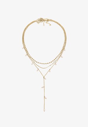 Aukso spalvos sluoksniuota kaklo grandinėlė, kurioje yra įvairių grandinių dizainų su subtiliais perlų akcentais, įskaitant lariat stiliaus pakabuką su išsibarsčiusiais perlais.