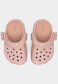 Ζευγάρι από ανοιχτό ροζ κλογκς Crocs με οπές αερισμού και ρυθμιζόμενα λουράκια στο τακούνι, σε λευκό φόντο, σε άποψη από πάνω.
