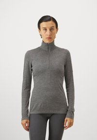 Sivá dlhá mikina na zips s vysokým golierom, vyrobená z hladkej, ľahkej tkaniny, s priliehavým strihom a minimálnymi švovými detailmi.