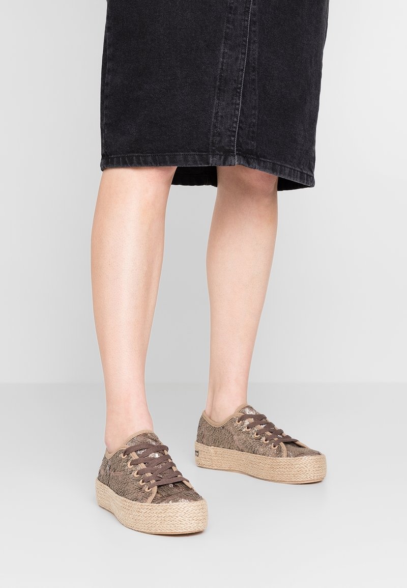 Baskets en toile texturée marron avec des lacets sombres et une semelle en corde de jute, à bout arrondi et au design profil bas.