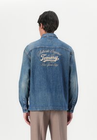 Denim jakna svijetloplave boje s dugim rukavima i klasičnom ovratnikom. Ima izvezeni "Tommy" logotip na leđima, s modernim detaljima šivanja.