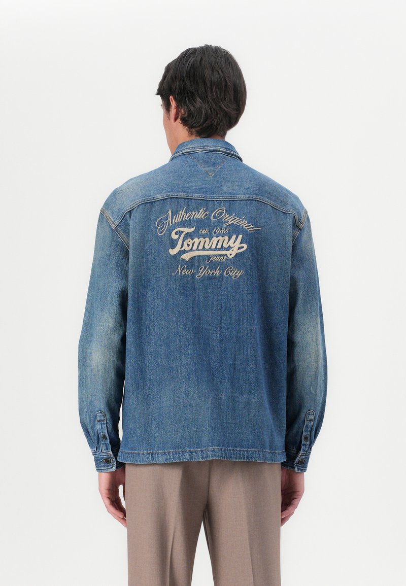 Denim jakna svijetloplave boje s dugim rukavima i klasičnom ovratnikom. Ima izvezeni "Tommy" logotip na leđima, s modernim detaljima šivanja.