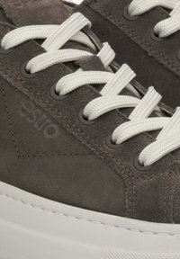 Ciemnoszare zamszowe sneakersy z białymi sznurowadłami, metalowymi oczkami i białą gumową podeszwą. Subtelny detal z logo widoczny z boku.