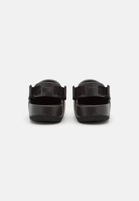 Sorte Nike sandaler med en glatt plastoverdel, justerbare stropper og såle av textured gummi med et mønstret spor.