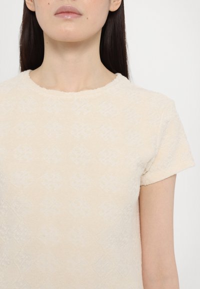 Ljust beige kortärmad topp i texturerad tyg, med ett subtilt diamantmönster och rund halsringning. Slät yta, mjuk känsla.